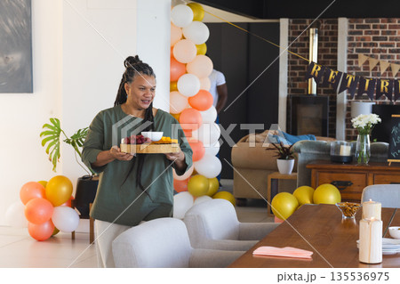Carrying tray with snacks, woman smiling at retirement party celebration Carrying tray with snacks, woman smiling at retirement party celebration 135536975