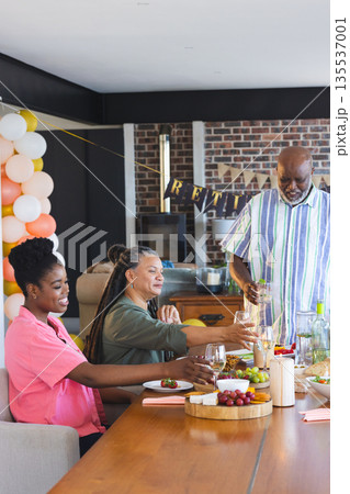 Family celebrating retirement with wine and laughter at home dining table Family celebrating retirement with wine and laughter at home dining table 135537001
