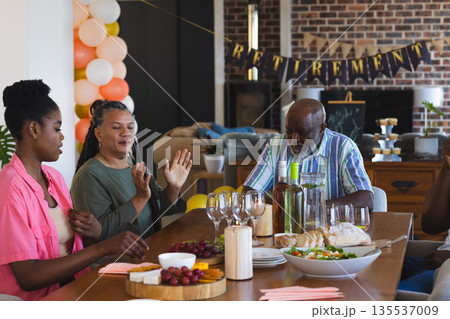 Celebrating retirement, family sharing food and drinks, having joyful conversation at home Celebrating retirement, family sharing food and drinks, having joyful conversation at home 135537009