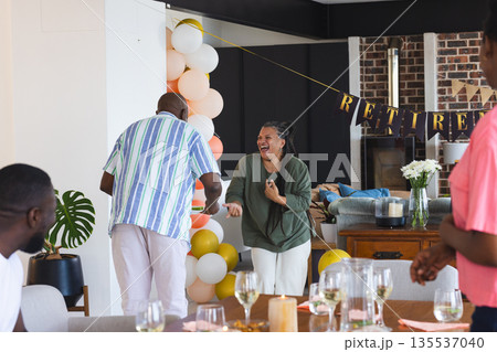 Family celebrating retirement at home, laughing and enjoying festive decorations 135537040