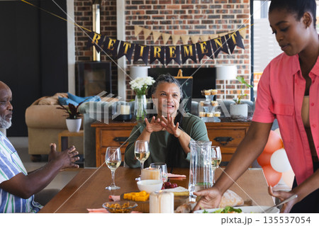 Family celebrating retirement with food and drinks at home, sharing joyful moments 135537054