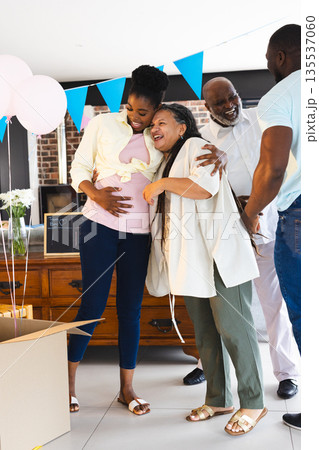 Family celebrating baby shower, smiling and embracing with balloons and decorations Family celebrating baby shower, smiling and embracing with balloons and decorations 135537060