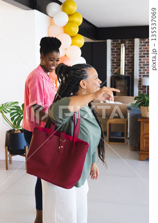 Women laughing and enjoying celebration at home with colorful balloons 135537069