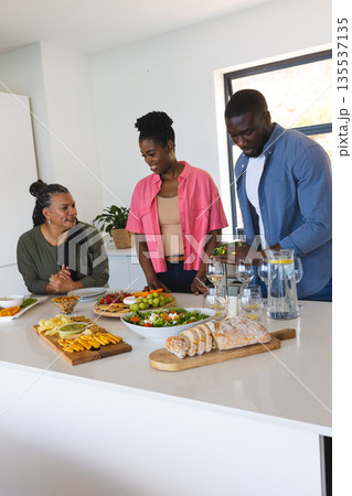 African American family preparing and enjoying meal together in modern kitchen 135537135