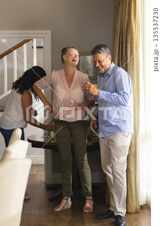 Seniors enjoying drinks and laughter at home during joyful celebration 135537230
