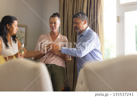 Celebrating at home, diverse seniors toasting with wine, enjoying togetherness Celebrating at home, diverse seniors toasting with wine, enjoying togetherness 135537241