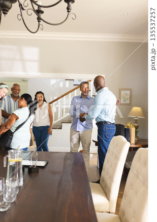Seniors gathering at home, shaking hands and smiling, celebrating together Seniors gathering at home, shaking hands and smiling, celebrating together 135537257