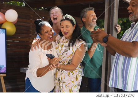 Seniors celebrating together outdoors, laughing and sharing moments with smartphone 135537276