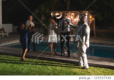 Celebrating by poolside, seniors raising glasses and having evening together 135537330