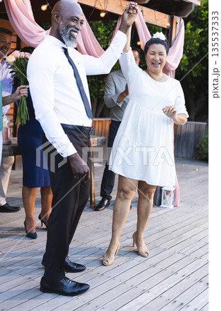 African American couple dancing joyfully at outdoor celebration with friends 135537333