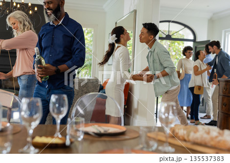 Guests enjoying lively conversation and drinks at home during wedding celebration 135537383
