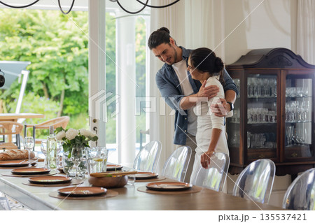 Couple embracing lovingly near elegantly set dining table in bright dining room 135537421