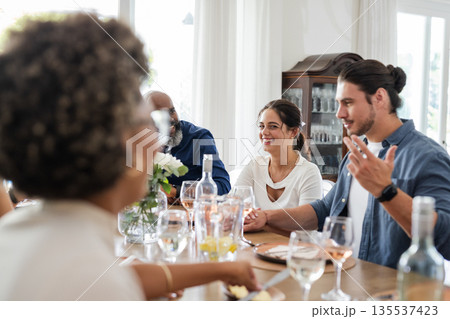Friends laughing and talking around dining table at wedding celebration 135537423