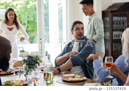 Friends enjoying lively conversation and delicious meal at elegant wedding reception 135537429