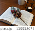 開いた洋書の上の松ぼっくりと赤い実 135538074