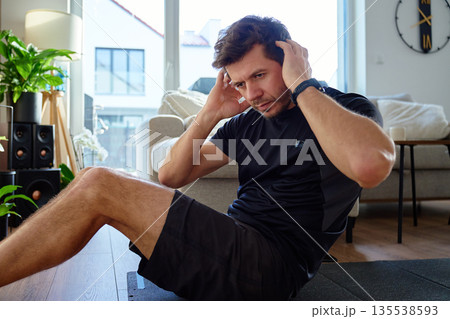 Man doing abdominal crunch exercise on fitness mat at home 135538593