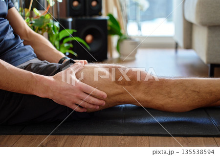 Man holding leg muscle after workout during home exercise 135538594