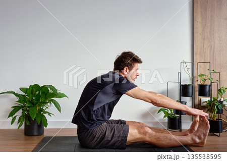 Man stretching during home workout in living room 135538595