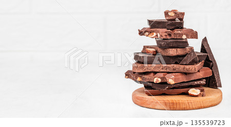 Stack of assorted chocolate pieces with nuts on white background 135539723