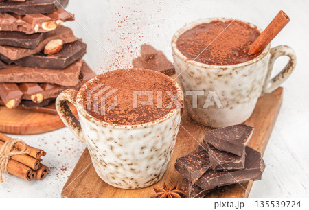 Two cups of hot chocolate with cocoa powder and chocolate pieces on white background Two cups of hot chocolate with cocoa powder and chocolate pieces on white background 135539724