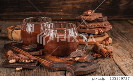 Two cups of hot chocolate with chocolate bars and spices on rustic wooden table Two cups of hot chocolate with chocolate bars and spices on rustic wooden table 135539727