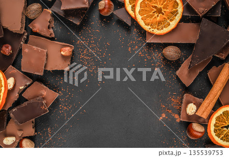 Dark chocolate background with cocoa powder, nuts and orange slices, copy space 135539753
