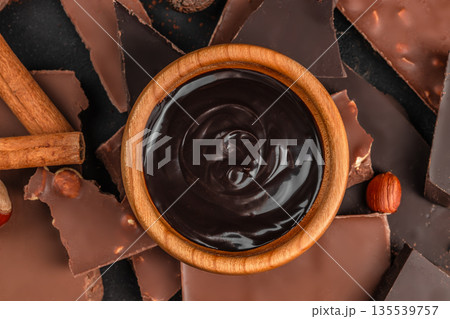 Dark chocolate sauce in bowl with chocolate pieces top view 135539757