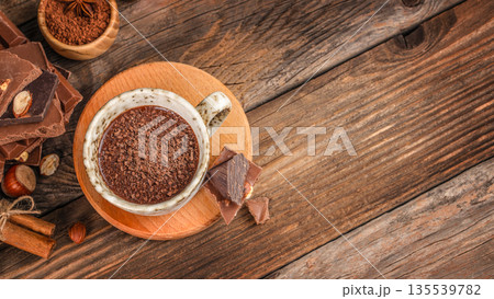 Hot chocolate topped with chocolate shavings in ceramic cup on wooden background, top view 135539782