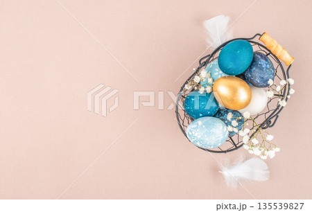 Elegant Easter flat lay with blue and gold eggs in wire basket on pastel background with copy space Elegant Easter flat lay with blue and gold eggs in wire basket on pastel background with copy space 135539827
