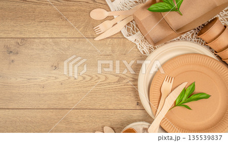 Eco friendly disposable tableware with wooden cutlery and paper plates on wooden background with copy space 135539837
