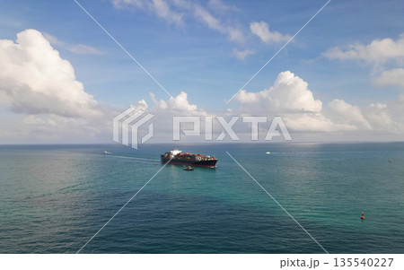 Cargo ship in sea, aerial view. Freight container loaded on cargo vessel. Aerial view cargo ship entering harbor. Cargo business. Container ship. Shipping logistics. Ocean freight transport 135540227