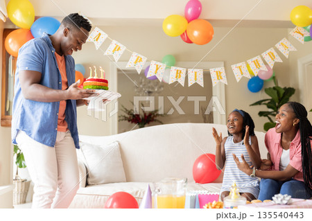 African American father bringing birthday cake while family celebrating at home African American father bringing birthday cake while family celebrating at home 135540443
