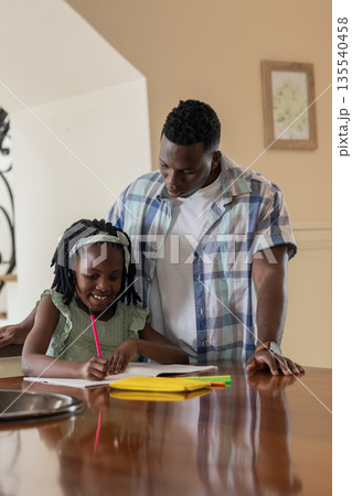 Helping daughter with homework, African American father and child at kitchen table Helping daughter with homework, African American father and child at kitchen table 135540458