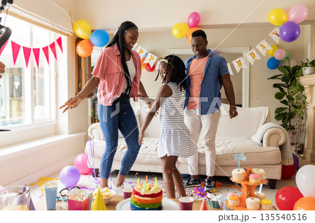 African American family celebrating birthday at home with balloons and cake 135540516