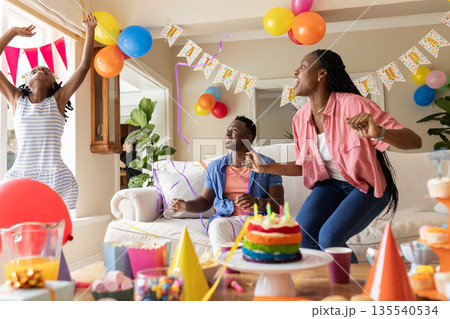 Joyful family dancing and laughing in colorful decorated living room for birthday 135540534