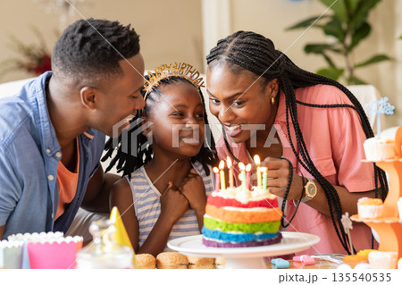 African American family celebrating birthday with colorful cake and joyful smiles African American family celebrating birthday with colorful cake and joyful smiles 135540535