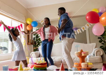 African American family celebrating birthday at home with balloons and cake African American family celebrating birthday at home with balloons and cake 135540537