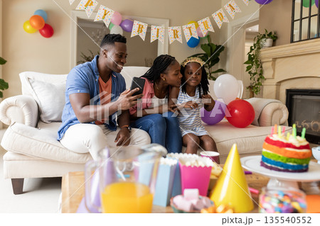 Celebrating birthday, happy family of three enjoying party with colorful decorations Celebrating birthday, happy family of three enjoying party with colorful decorations 135540552