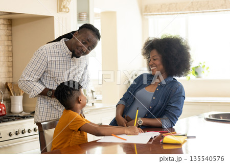 Family enjoying quality time at home, child drawing while parents happily watching 135540576