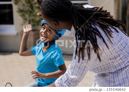Father teaching son to ride bicycle, celebrating success with high five Father teaching son to ride bicycle, celebrating success with high five 135540642