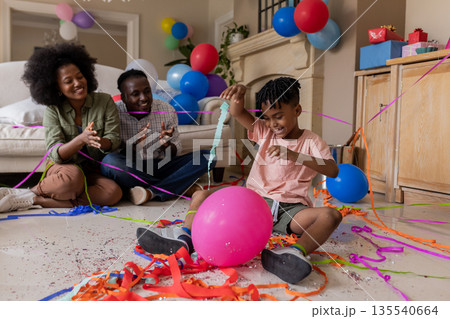 African American family celebrating birthday at home with balloons and streamers 135540664