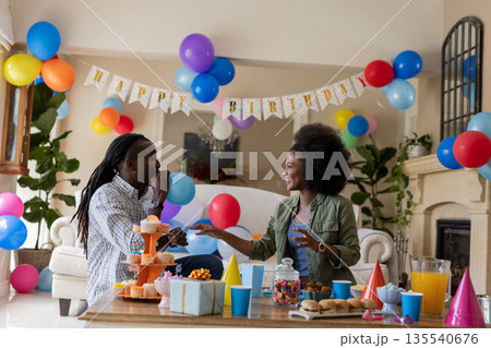 Celebrating birthday, African American couple with colorful balloons at party indoors Celebrating birthday, African American couple with colorful balloons at party indoors 135540676