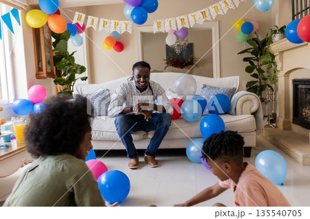 Celebrating birthday, African American family with colorful balloons and decorations at home 135540705