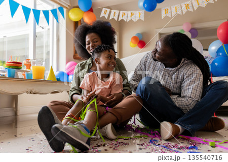 Family celebrating birthday at home, smiling and surrounded by colorful decorations Family celebrating birthday at home, smiling and surrounded by colorful decorations 135540716