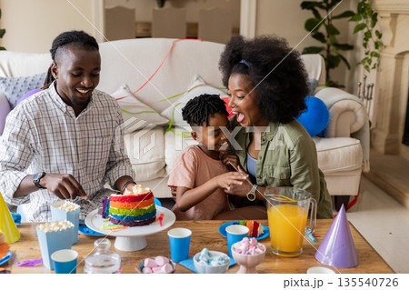 Celebrating birthday, happy family enjoying cake and laughter at home together 135540726