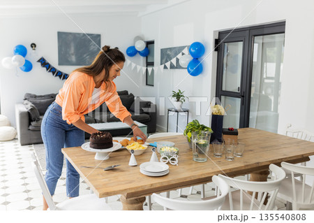 Woman preparing birthday table with cake and decorations at home celebration Woman preparing birthday table with cake and decorations at home celebration 135540808