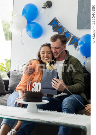 Celebrating birthday, couple hugging and exchanging gift with joy at home Celebrating birthday, couple hugging and exchanging gift with joy at home 135540880