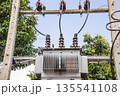 Electrical transformer and power lines on utility pole in tropical Thailand landscape, energy infrastructure surrounded by green trees and clear sky 135541108