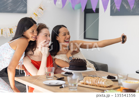 Laughing and taking selfie, three young women celebrate at birthday party 135541556
