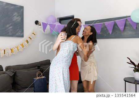 Hugging each other warmly, three young women celebrate birthday at home Hugging each other warmly, three young women celebrate birthday at home 135541564